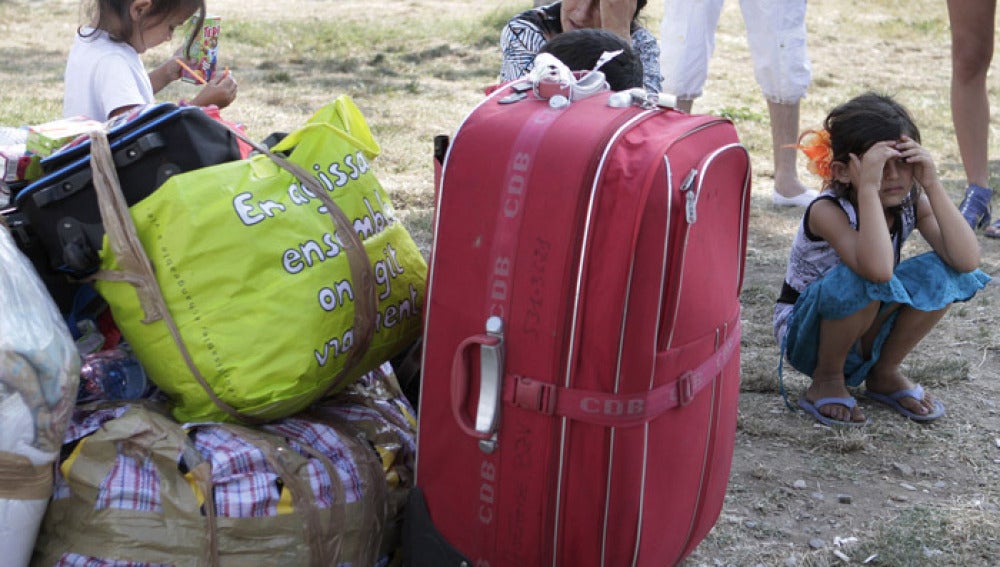 Una familia de rumanos espera tras ser desalojada de su residencia en Francia.