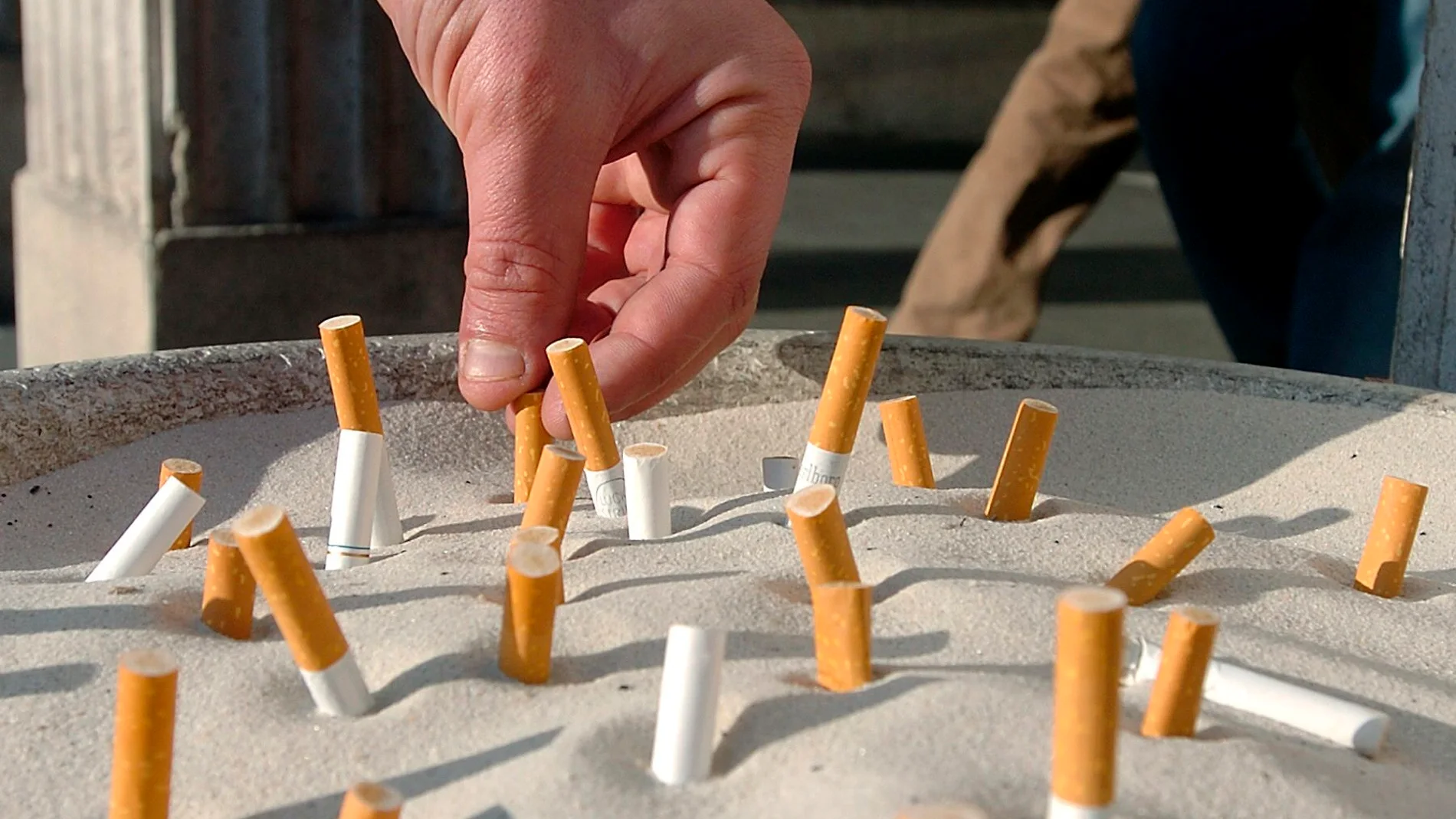 Un hombre apaga un cigarrillo en un cenicero Un hombre apaga un cigarrillo en un cenicero