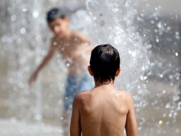 Niños se bañan para soportar el calor