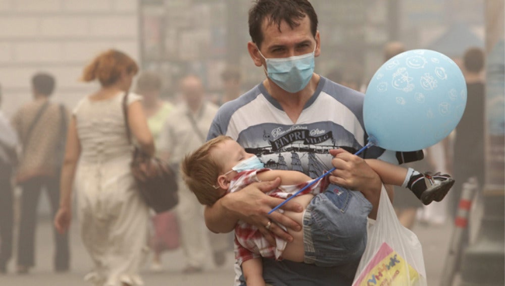 Un padre y su hijo, protegidos por mascarillas, pasean por las calles de Moscú