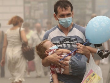 Un padre y su hijo, protegidos por mascarillas, pasean por las calles de Moscú