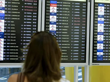 Una mujer observa la pantalla de vuelos en un aeropuerto Una mujer observa la pantalla de vuelos en un aeropuerto