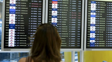 Una mujer observa la pantalla de vuelos en un aeropuerto