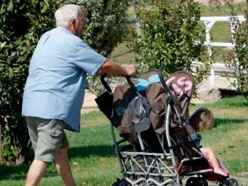 Un abuelo paseando a sus nietos