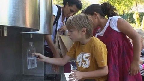 Un ni&ntilde;o rellena su botella en la fuente de agua con gas