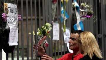 Dos personas colocan un ramo de flores en reconocimiento al fallecido ex presidente