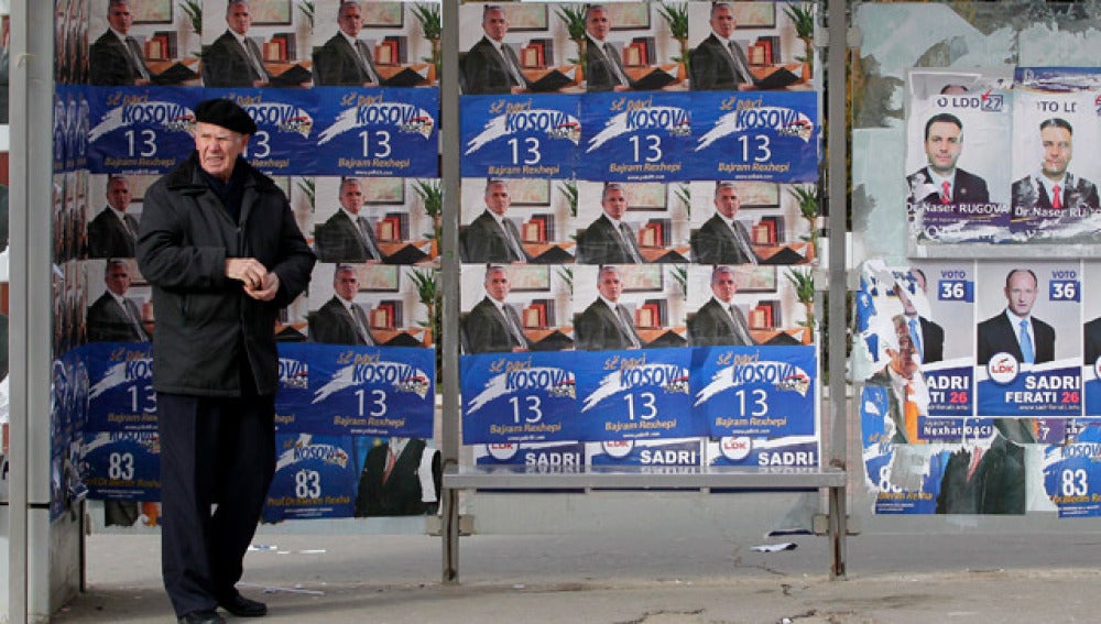  Un hombre camina frente a unos carteles electorales del Partido Democrático (PDK)