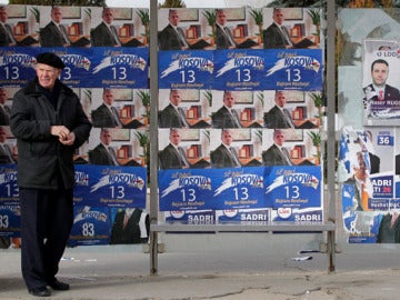  Un hombre camina frente a unos carteles electorales del Partido Democrático (PDK)