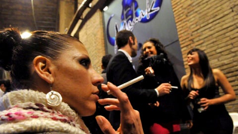 Una joven fuma a las puertas de un pub