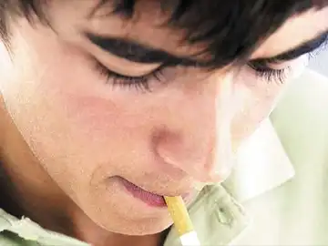 Un joven fumando un cigarrillo Un joven fumando un cigarrillo