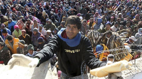 Un voluntario reparte pan entre los refugiados en la frontera