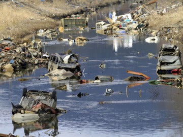  Coches, camiones y otros escombros sumergidos en el agua de un canal fluvial en Ichinomaki