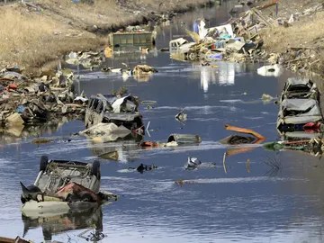 Coches, camiones y otros escombros sumergidos en el agua de un canal fluvial en Ichinomaki Coches, camiones y otros escombros sumergidos en el agua de un canal fluvial en Ichinomaki