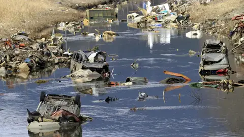 Coches, camiones y otros escombros sumergidos en el agua de un canal fluvial en Ichinomaki Coches, camiones y otros escombros sumergidos en el agua de un canal fluvial en Ichinomaki