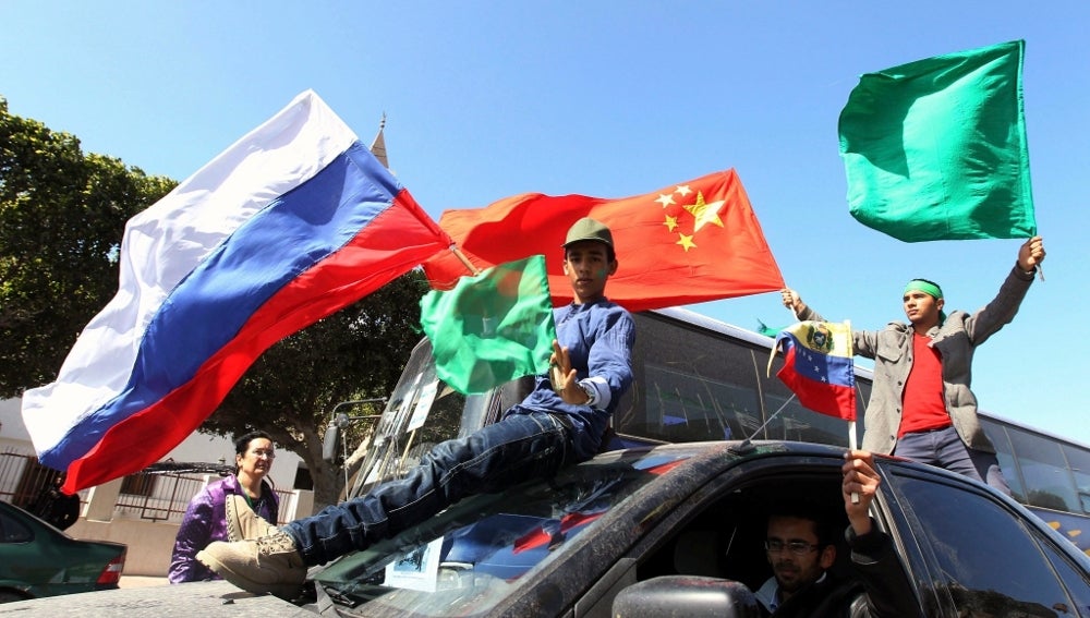 Partidarios de Gadafi ondean la bandera Libia junto a las de China y Rusia