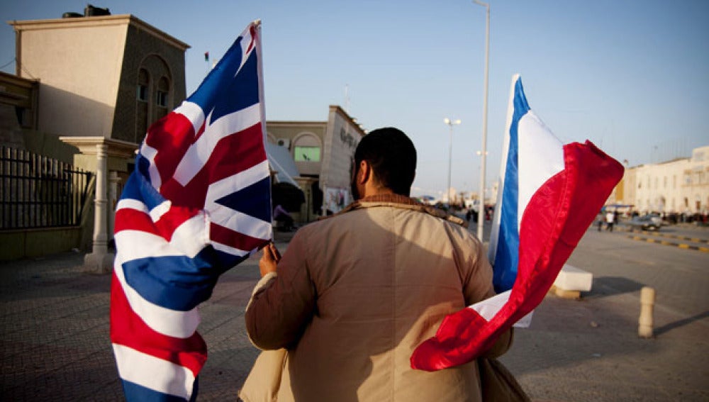 Un hombre camina en Bengasi con las banderas de Reino Unido y Francia