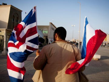 Un hombre camina en Bengasi con las banderas de Reino Unido y Francia