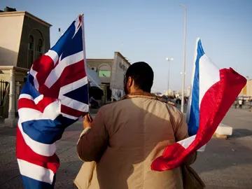 Un hombre camina en Bengasi con las banderas de Reino Unido y Francia Un hombre camina en Bengasi con las banderas de Reino Unido y Francia