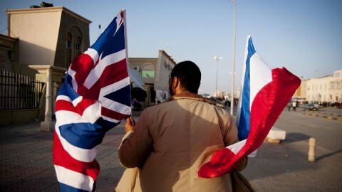 Un hombre camina en Bengasi con las banderas de Reino Unido y Francia