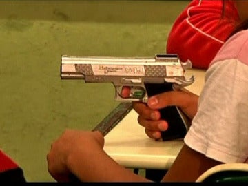 Una niña de un colegio de Brasil sujeta un arma.