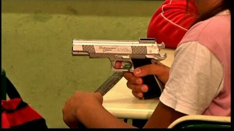 Una ni&ntilde;a de un colegio de Brasil sujeta un arma.