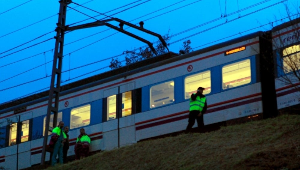 Varios operarios junto a un tren de Cercanías de Renfe.