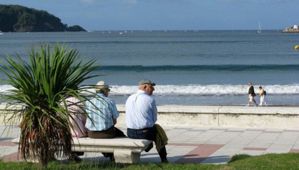 Unos jubilados sentados en un banco frente a la playa