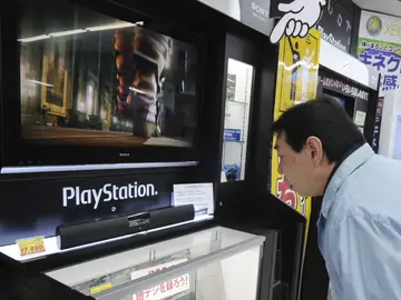 Un hombre observa una consola de PlayStation Un hombre observa una consola de PlayStation