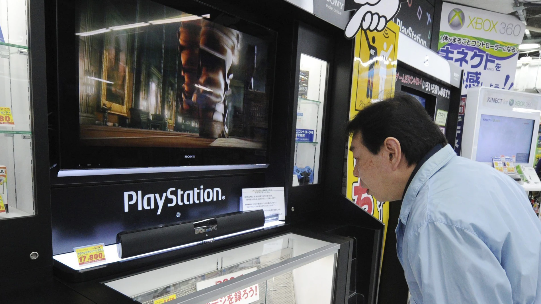 Un hombre observa una consola de PlayStation Un hombre observa una consola de PlayStation