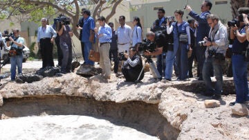 Los reporteros gráficos observan el crater causado por un bombardeo de la OTAN en Bab al-Aziziya. 