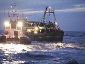 Guardias costeros ayudan a una embarcación procedente de Libia