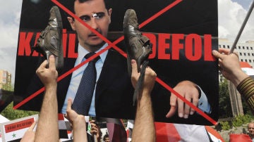 Manifestantes turcos y sirios enarbolan una pancarta en contra de Bachar al Asad.