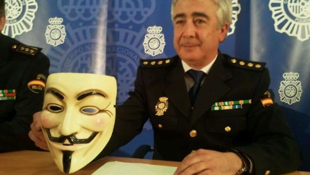 Comisario de la Brigada de Investigación Tecnológica sosteniendo una careta de Anonymous