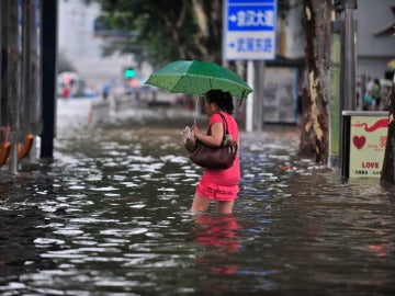 Una mujer camina por una calle inundada hacia una parada de autobús en Wuhan