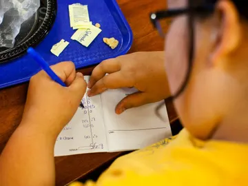 Niño haciendo los deberes después de comer Niño haciendo los deberes después de comer