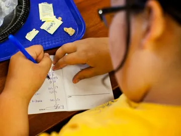 Niña haciendo los deberes después de comer Niña haciendo los deberes después de comer