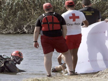 Miembros de la Cruz Roja y de la Guardia Civil sacan del agua el cuerpo sin vida de uno de uno de los niños.