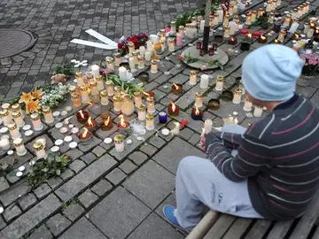 Un joven sentado en un banco junto a una multitud de velas Un joven sentado en un banco junto a una multitud de velas