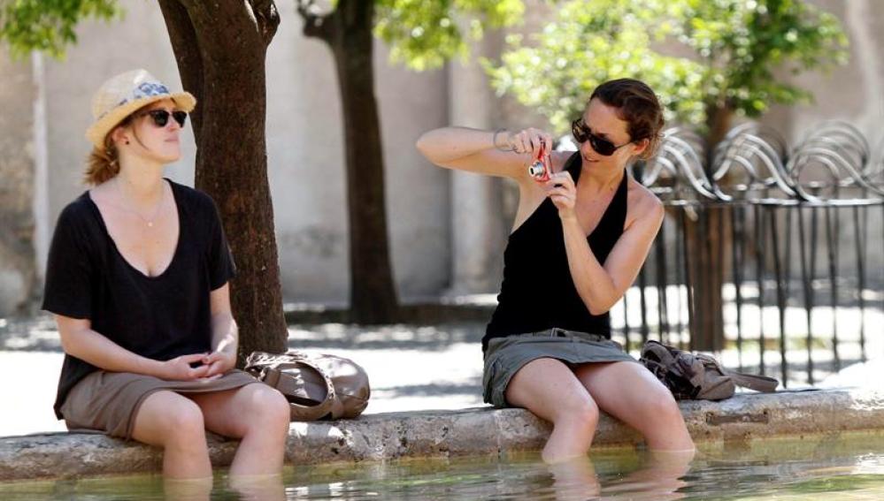 Dos turistas se refrescan en una de las fuentes del patio de Los Naranjos