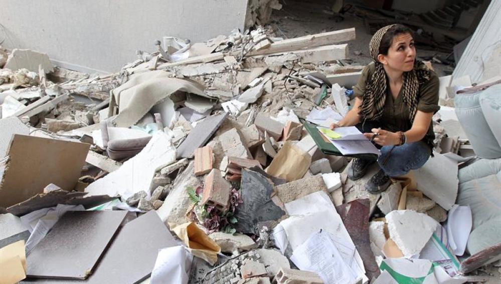 Una periodista extranjera toma notas entre los escombros de un edificio gubernamental atacado por la OTAN