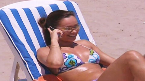 Una joven habla por el m&oacute;vil en la playa.