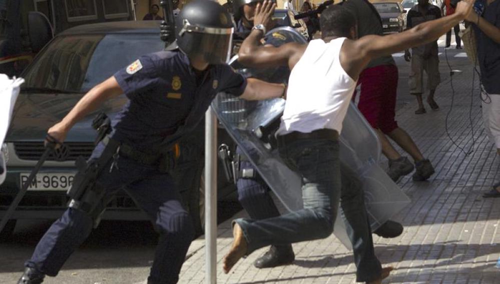 Un efectivo antidisturbio de la Policía Nacional intenta detener a un ciudadano nigeriano