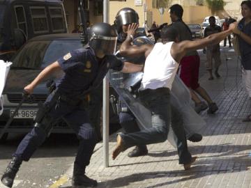 Un efectivo antidisturbio de la Policía Nacional intenta detener a un ciudadano nigeriano