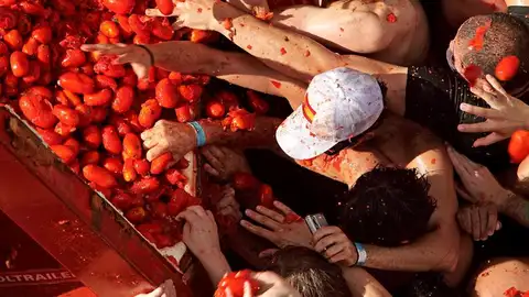 Varias personas cogen los tomates que caen del remolque Varias personas cogen los tomates que caen del remolque
