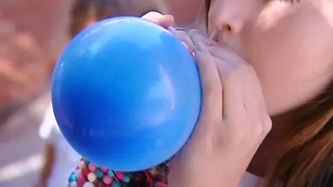 Un niño inflando un globo. Un niño inflando un globo.