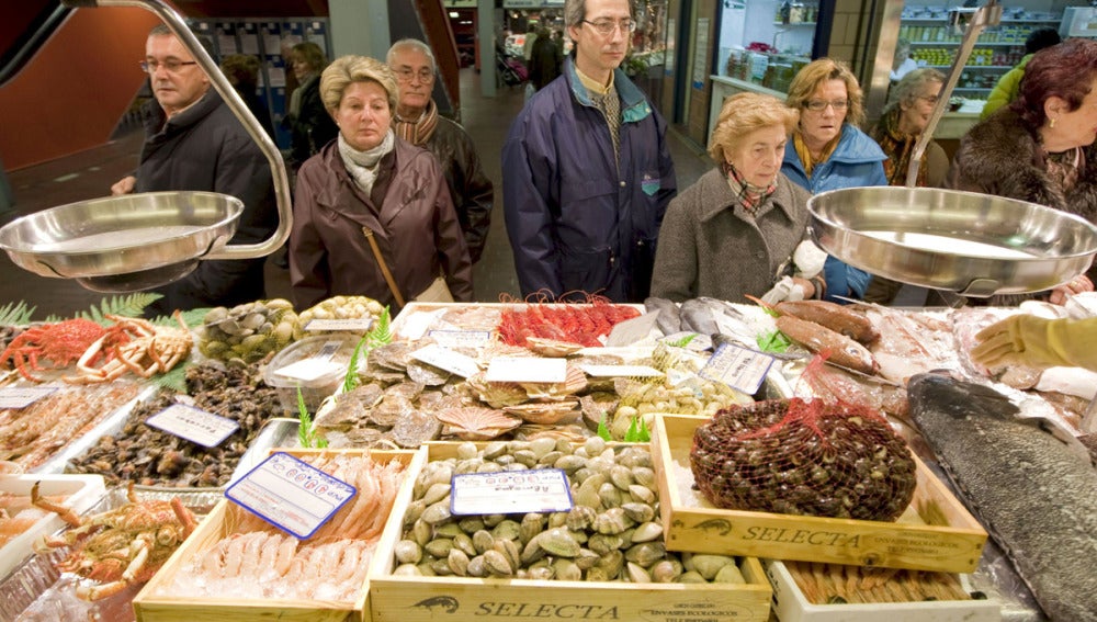 Un grupo de personas hacen cola ante una pescadería en el Mercado de Vitoria