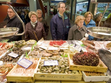 Un grupo de personas hacen cola ante una pescadería en el Mercado de Vitoria
