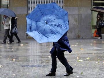 Una mujer se protege de la lluvia y el viento