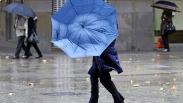 Una mujer se protege de la lluvia y el viento