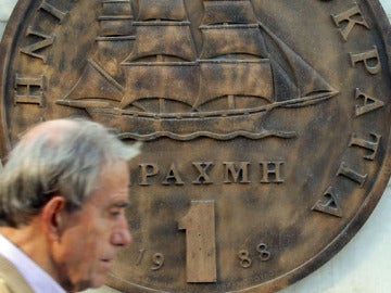 Un hombre camina frente al drachma griego 